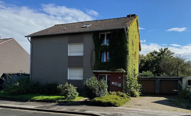 Mehrfamilienhaus mit efeubewachsener Fassade und Garagen