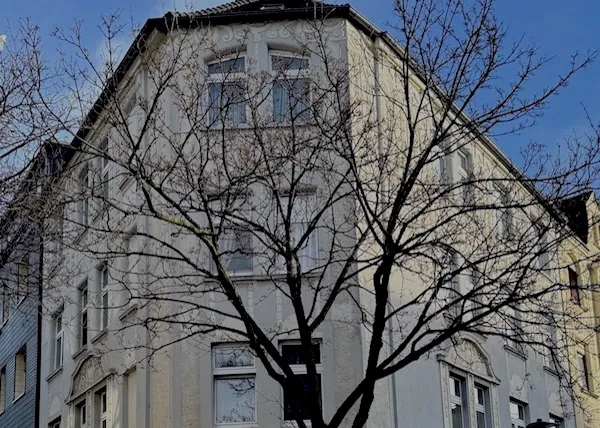 Altbau-Mehrfamilienhaus hinter einem Baum