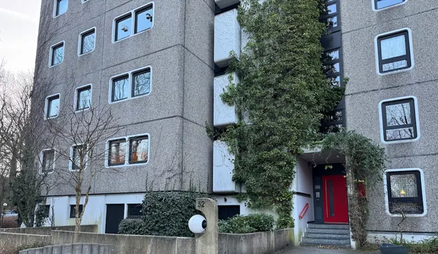 Mehrfamilienhaus mit begrünter Fassade und rotem Hauseingang